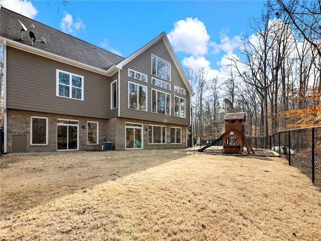 back of house featuring central AC, brick siding, a playground, and fence