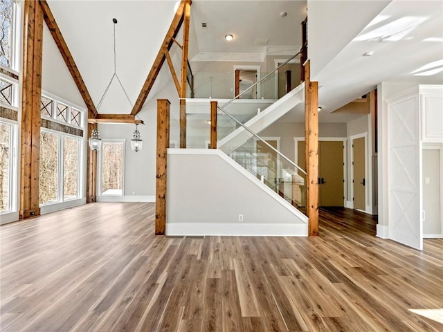 interior space with a chandelier, high vaulted ceiling, wood finished floors, baseboards, and stairway