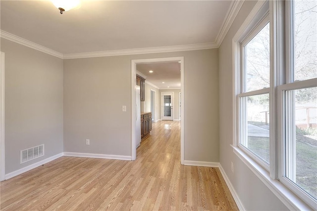 unfurnished room with light wood-style flooring, baseboards, visible vents, and ornamental molding