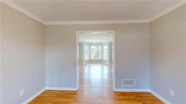 unfurnished room featuring visible vents, baseboards, crown molding, and light wood-style floors