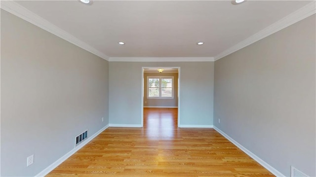 spare room featuring visible vents, baseboards, ornamental molding, and light wood finished floors