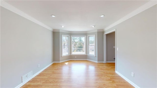 unfurnished room featuring visible vents, baseboards, light wood-style flooring, and ornamental molding