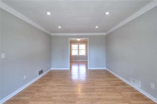 empty room with visible vents, baseboards, light wood-style flooring, and crown molding