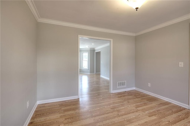 empty room with visible vents, baseboards, light wood-style flooring, and crown molding