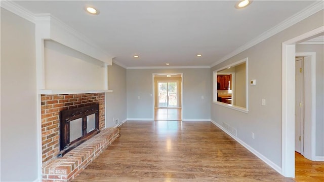 unfurnished living room featuring baseboards, a brick fireplace, wood finished floors, and ornamental molding