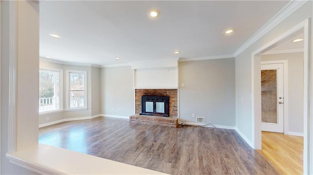 unfurnished living room featuring a brick fireplace, crown molding, baseboards, and wood finished floors