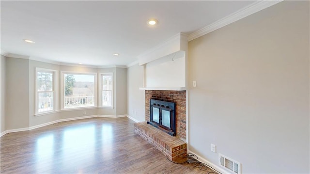 unfurnished living room with crown molding, a brick fireplace, wood finished floors, and visible vents