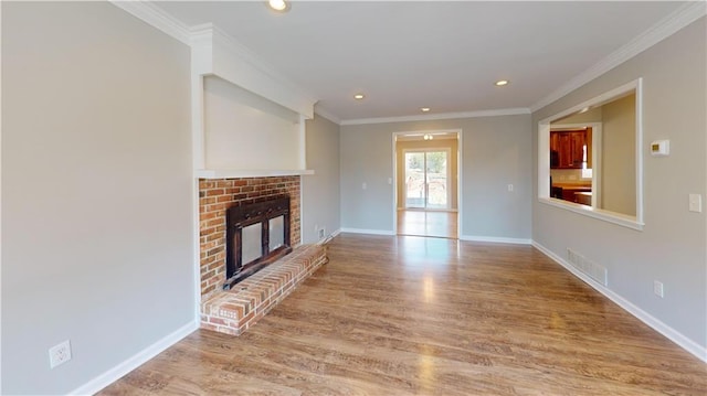 unfurnished living room featuring crown molding, a brick fireplace, wood finished floors, and visible vents