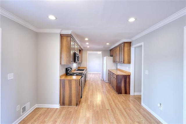 kitchen with light wood-type flooring, black range with electric stovetop, a sink, freestanding refrigerator, and light countertops