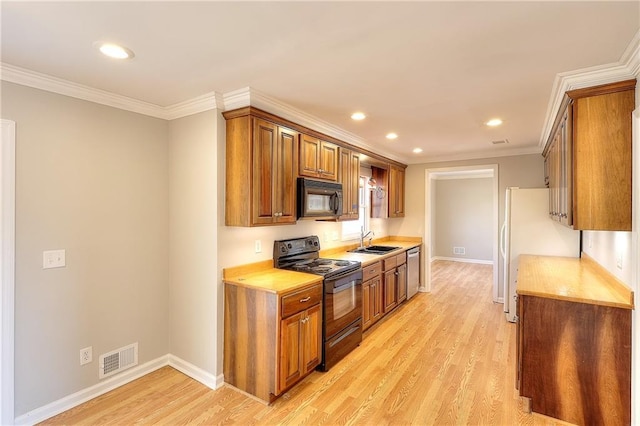 kitchen with a sink, black appliances, light wood-style flooring, and ornamental molding