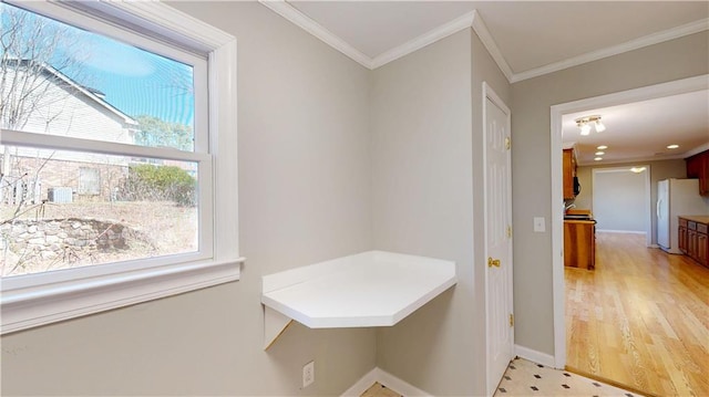 interior space with light wood finished floors, baseboards, and ornamental molding