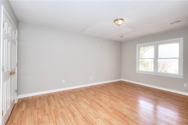 spare room with visible vents, light wood-type flooring, and baseboards