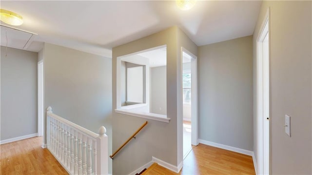 hall featuring attic access, wood finished floors, an upstairs landing, and baseboards