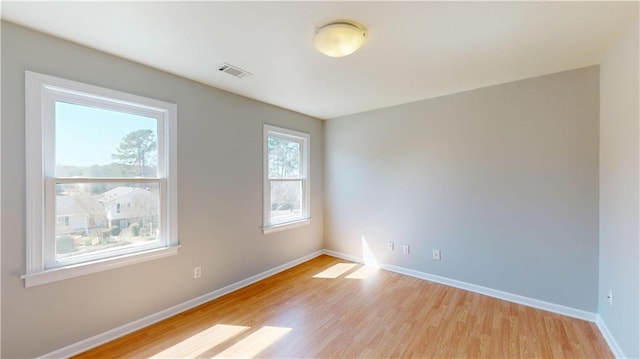 unfurnished room featuring visible vents, light wood-type flooring, and baseboards