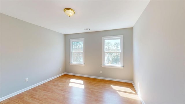 unfurnished room featuring light wood-style floors, visible vents, and baseboards