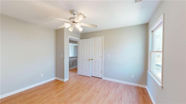 unfurnished bedroom featuring a closet, light wood-style flooring, a ceiling fan, and baseboards