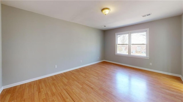 empty room featuring visible vents, baseboards, and light wood-style floors