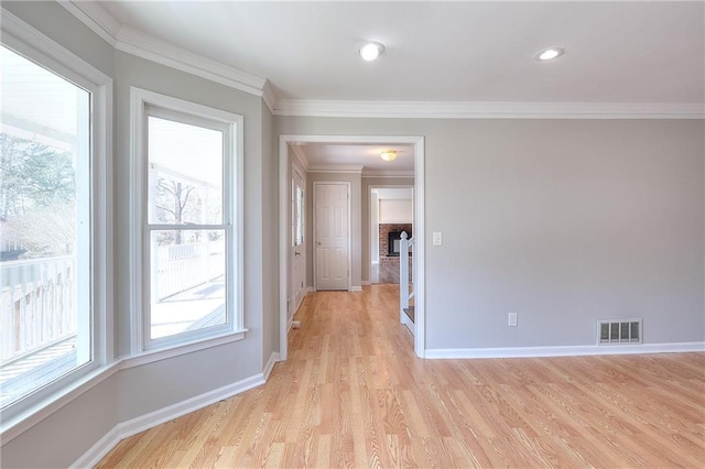 empty room with visible vents, baseboards, ornamental molding, and light wood finished floors