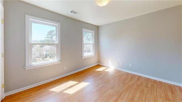 unfurnished room featuring visible vents, baseboards, and light wood-style floors