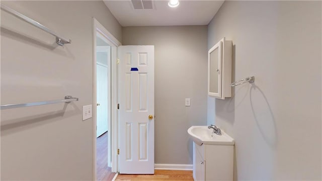 bathroom featuring visible vents, vanity, baseboards, and wood finished floors