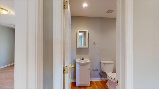 bathroom featuring vanity, wood finished floors, visible vents, baseboards, and toilet