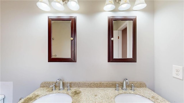 bathroom featuring double vanity, toilet, and a sink