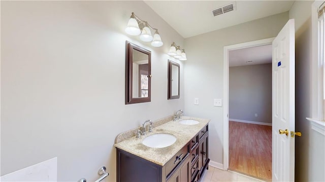 full bathroom with double vanity, baseboards, visible vents, and a sink