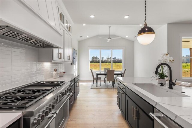 kitchen featuring stainless steel appliances, sink, pendant lighting, white cabinetry, and lofted ceiling