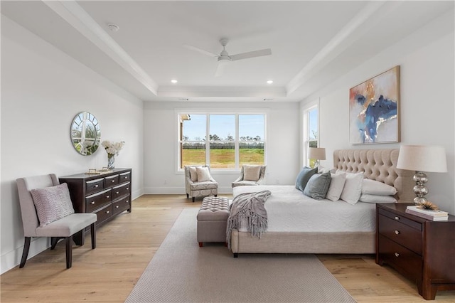 bedroom with a tray ceiling, light hardwood / wood-style flooring, and ceiling fan