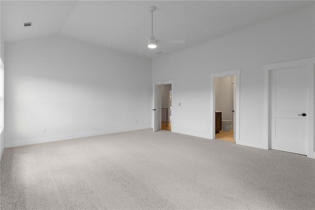 unfurnished bedroom featuring ensuite bathroom, ceiling fan, light colored carpet, and vaulted ceiling