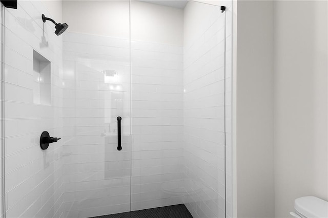 bathroom featuring a shower with shower door and toilet