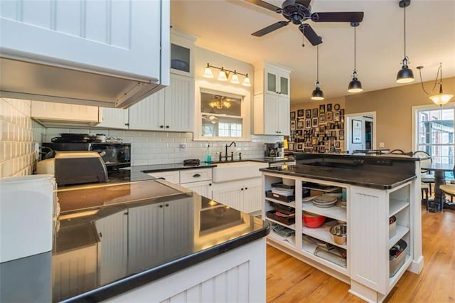 kitchen featuring pendant lighting, open shelves, dark countertops, glass insert cabinets, and white cabinets