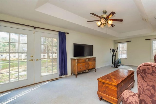 carpeted living room with baseboards, a raised ceiling, a ceiling fan, and french doors