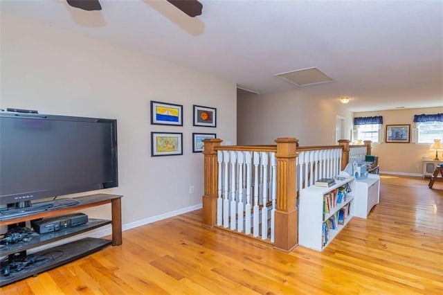 hall with an upstairs landing, baseboards, and light wood finished floors