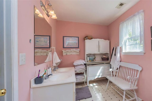 bathroom with double vanity, visible vents, an inviting chandelier, a sink, and tile patterned floors