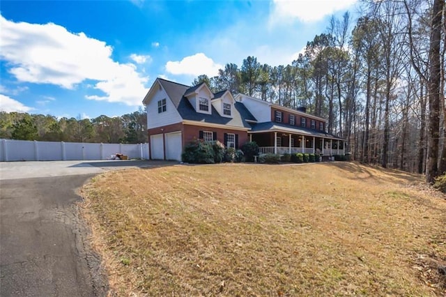 view of front of home with aphalt driveway, a porch, an attached garage, fence, and a front yard