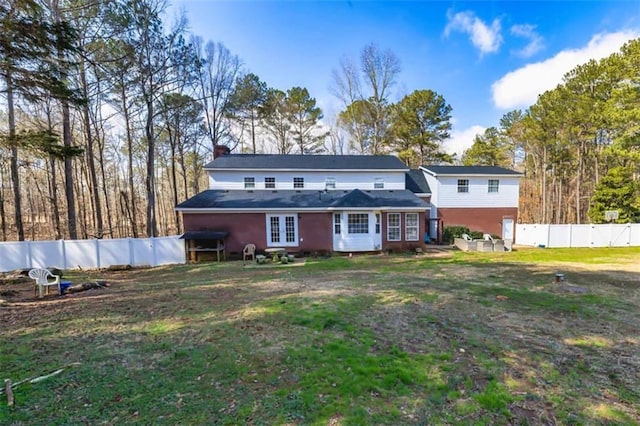 rear view of property featuring a yard, french doors, and fence