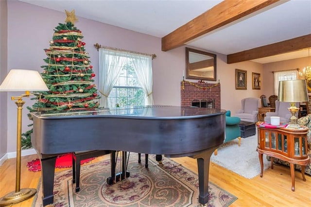 sitting room featuring a fireplace, wood finished floors, and beamed ceiling