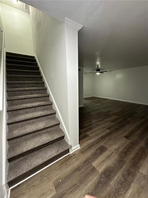 staircase featuring ceiling fan, baseboards, and wood finished floors