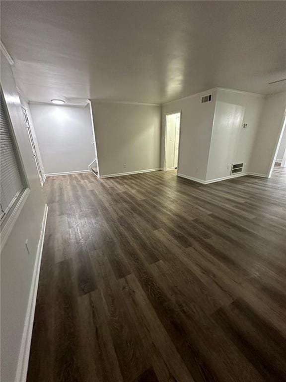 interior space with dark wood-type flooring, visible vents, and baseboards