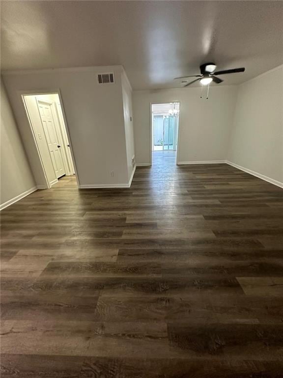 unfurnished room featuring a ceiling fan, dark wood-style flooring, visible vents, and baseboards