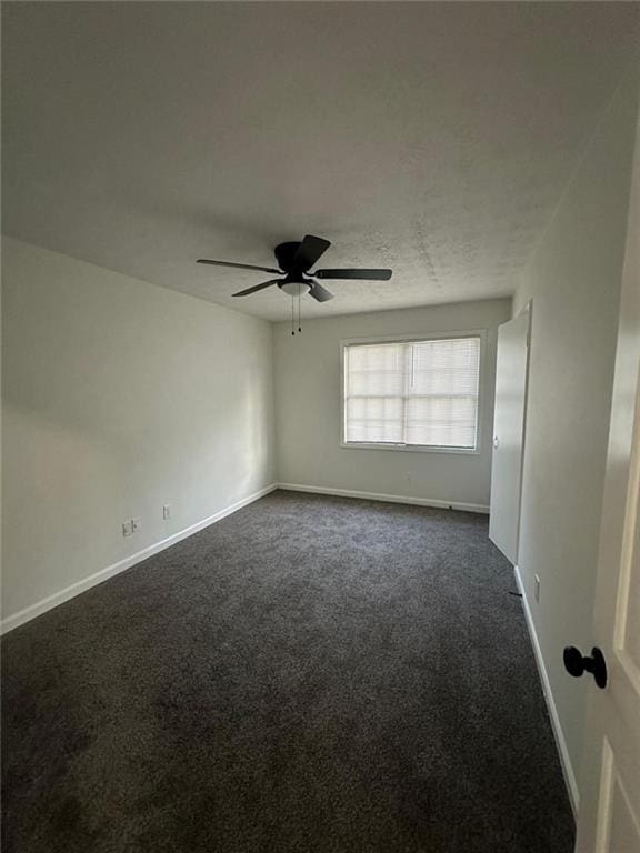 unfurnished room featuring ceiling fan, baseboards, dark colored carpet, and a textured ceiling