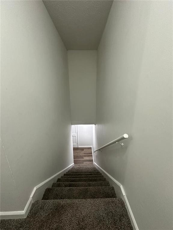 stairs featuring baseboards and a textured ceiling