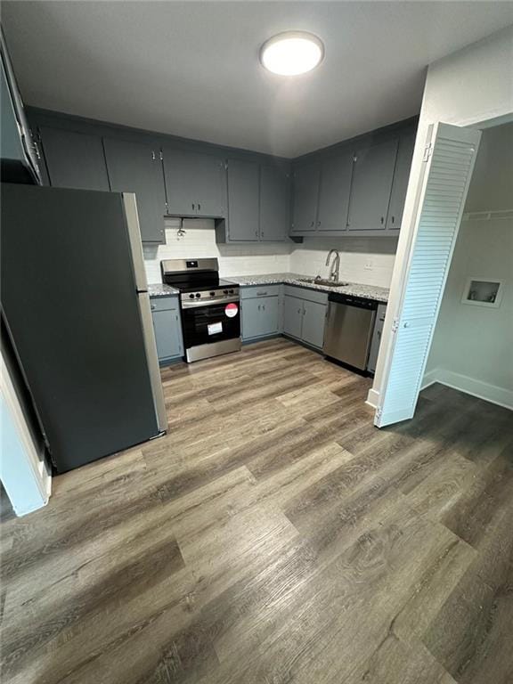 kitchen featuring stainless steel appliances, light wood-type flooring, gray cabinets, and light countertops