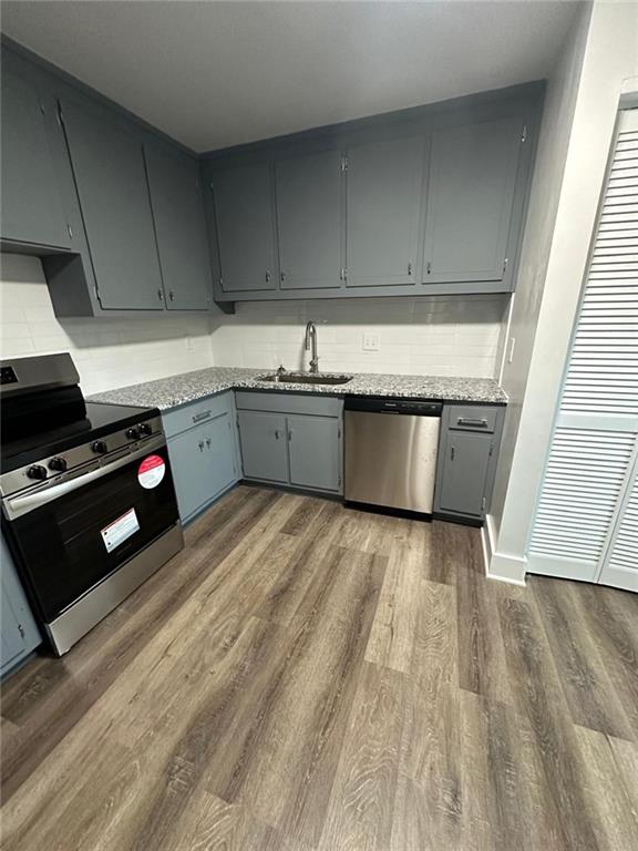 kitchen with dark wood-style flooring, a sink, appliances with stainless steel finishes, gray cabinets, and decorative backsplash