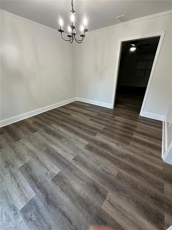 unfurnished dining area with ornamental molding, a notable chandelier, baseboards, and dark wood-style floors