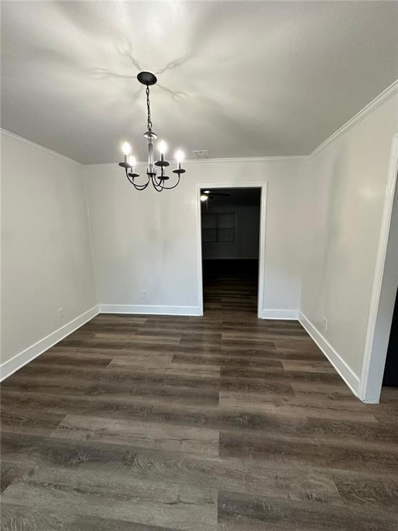 unfurnished dining area featuring crown molding, baseboards, a chandelier, and dark wood-type flooring