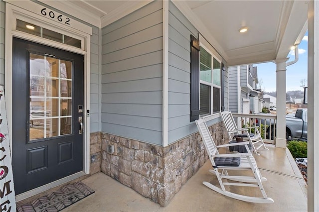 view of exterior entry with stone siding and a porch