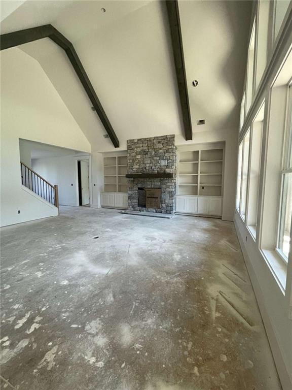 1210 Askew Trl, Greensboro, GA 30642 - unfurnished living room featuring a stone fireplace, unfinished concrete flooring, high vaulted ceiling, and built in shelves