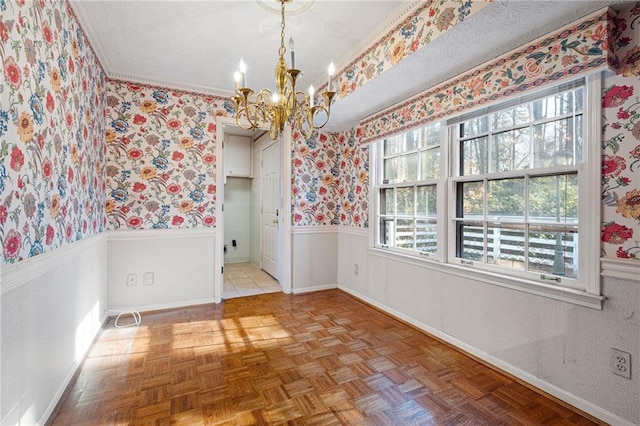 empty room with light parquet floors, ornamental molding, and a chandelier